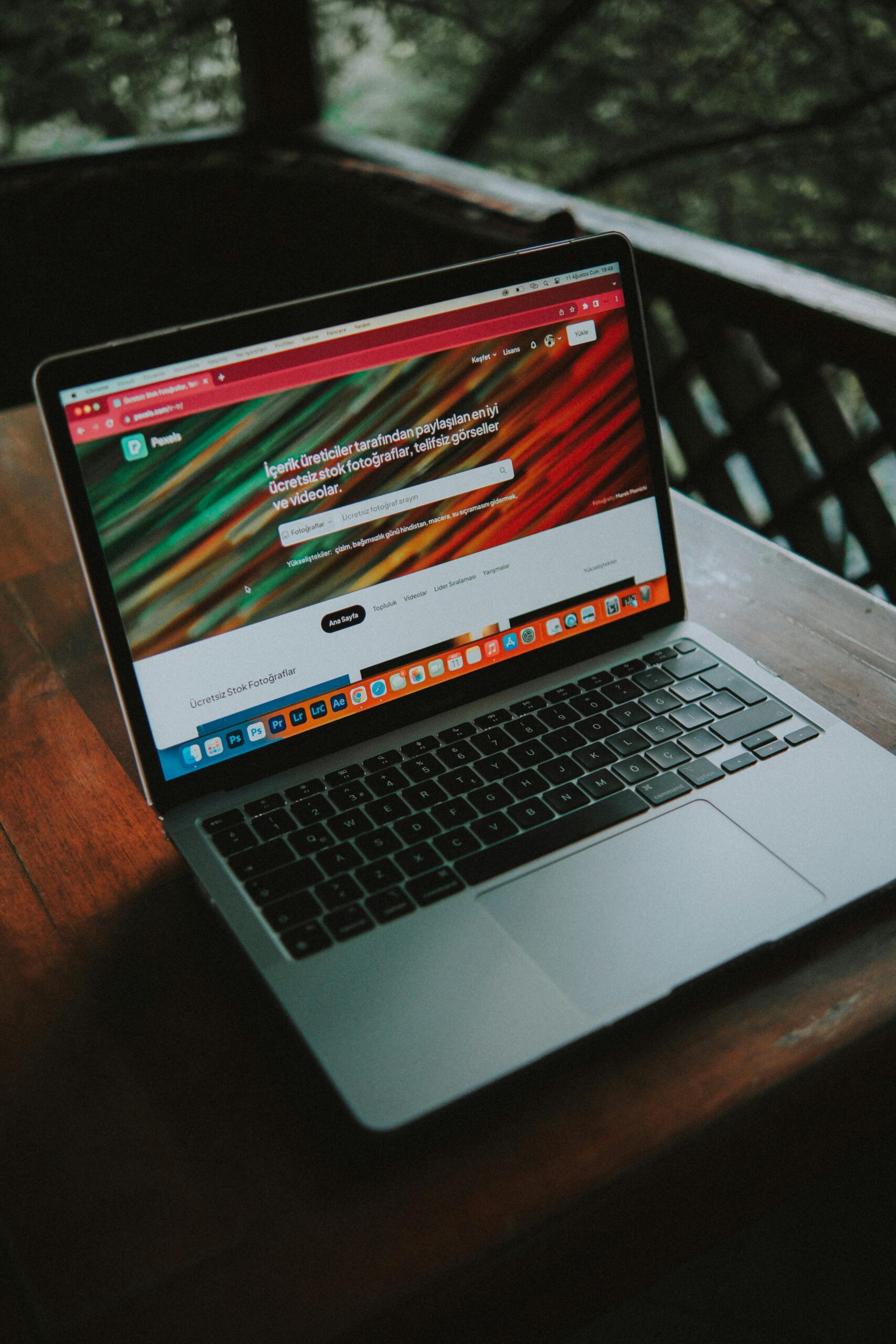 A close-up view of a laptop with a website open, placed on a wooden table near a window.