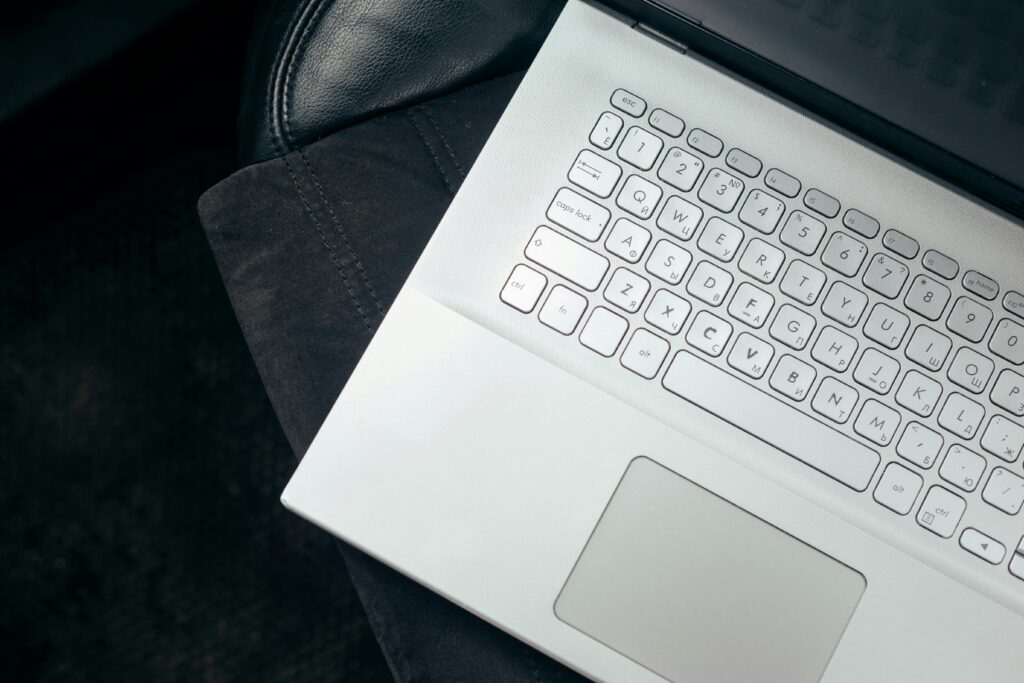 Top view of a sleek white laptop on a leather car seat, emphasizing modern technology and style.